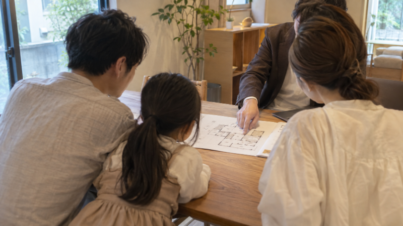 打ち合わせスペースで担当者と間取り図を見ながら話す家族